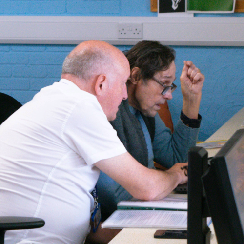 Norman supporting a male client in the centre to use a laptop
